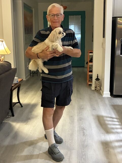 A supporter holding his dog and wearing a single white sock at home